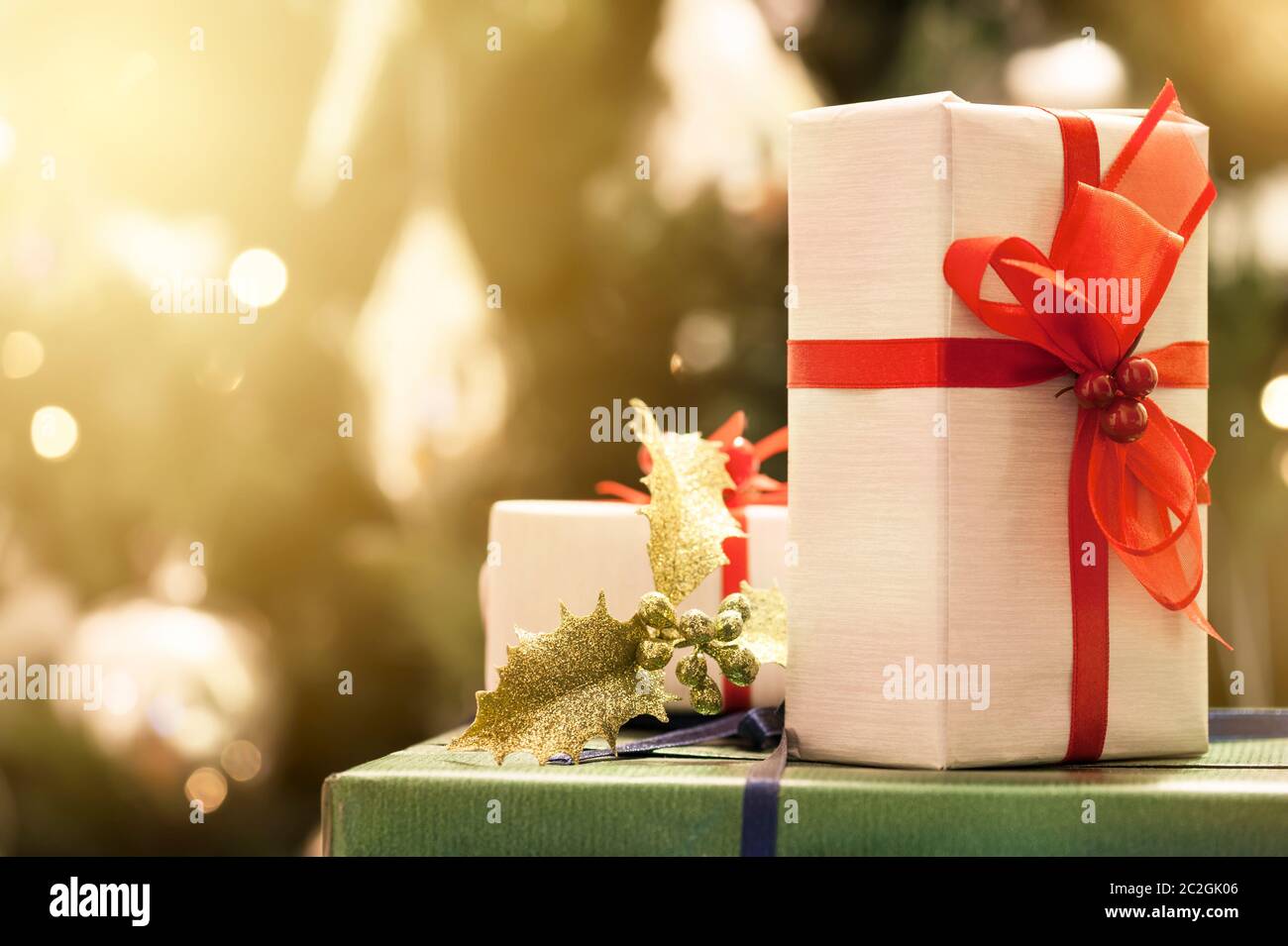 Decorated gift boxes with lighted christmas tree on background Stock Photo