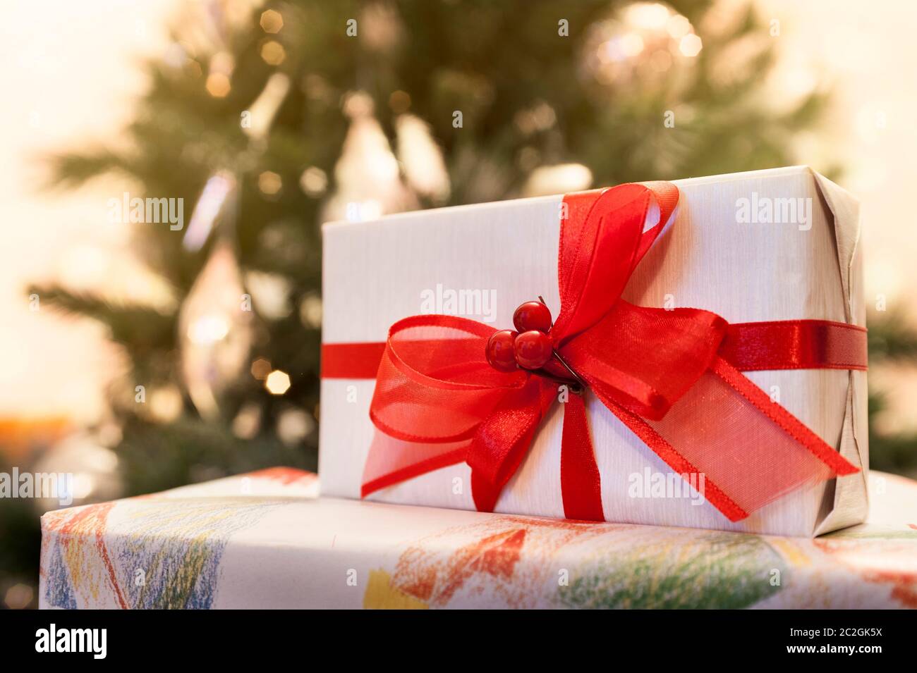 Decorated gift boxes with lighted christmas tree on background Stock Photo