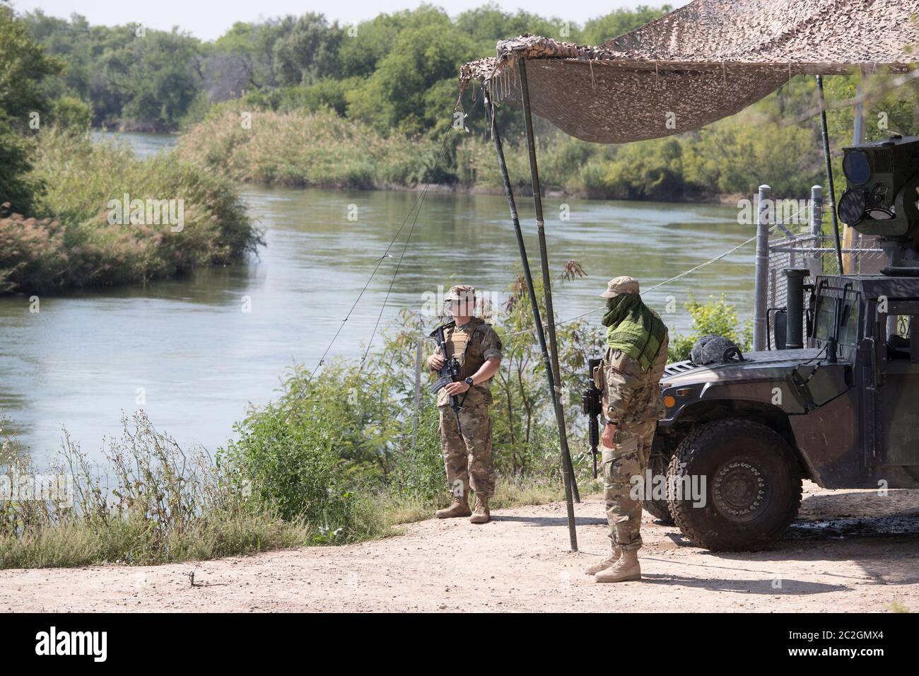 Roma Texas April 13, 2018: Texas National Guard troops man a observation post along the Rio Grande River as it flows southward between the bluffs of Roma and the Mexican city of Ciudad Miguel Aleman to the left.  Over a thousand National Guard troops were called up to enhance border security in Texas. ©Bob Daemmrich Stock Photo