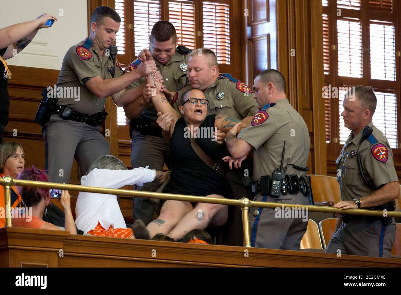 Austin Texas USA, July 2013: A protester is dragged from the public gallery by Texas Dept. of Public Safety troopers after a final House vote on a bill HB2 that further restricts abortion providers in Texas. The woman violated a House rule banning protests inside the chamber. Pro-life and pro-choice advocates have flooded the Texas Capitol with marches and protests the last two weeks.  ©Bob Daemmrich Stock Photo