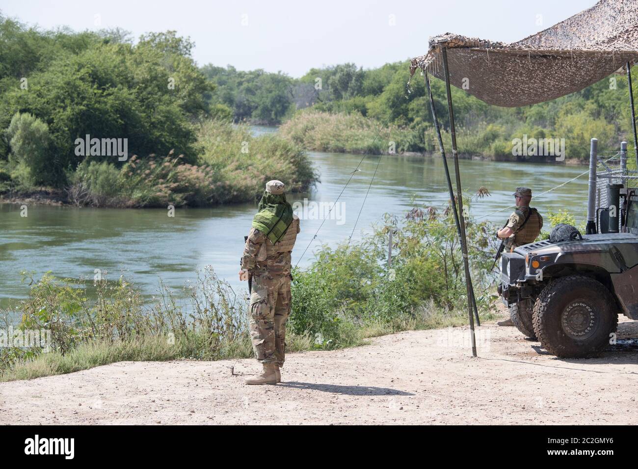Roma Texas April 13, 2018: Texas National Guard troops man a observation post along the Rio Grande River as it flows southward between the bluffs of Roma and the Mexican city of Ciudad Miguel Aleman to the left.  Over a thousand National Guard troops were called up to enhance border security in Texas. ©Bob Daemmrich Stock Photo