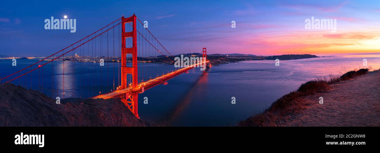 Golden Gate Bridge in San Francisco under full moon in sunset sky panorama Stock Photo