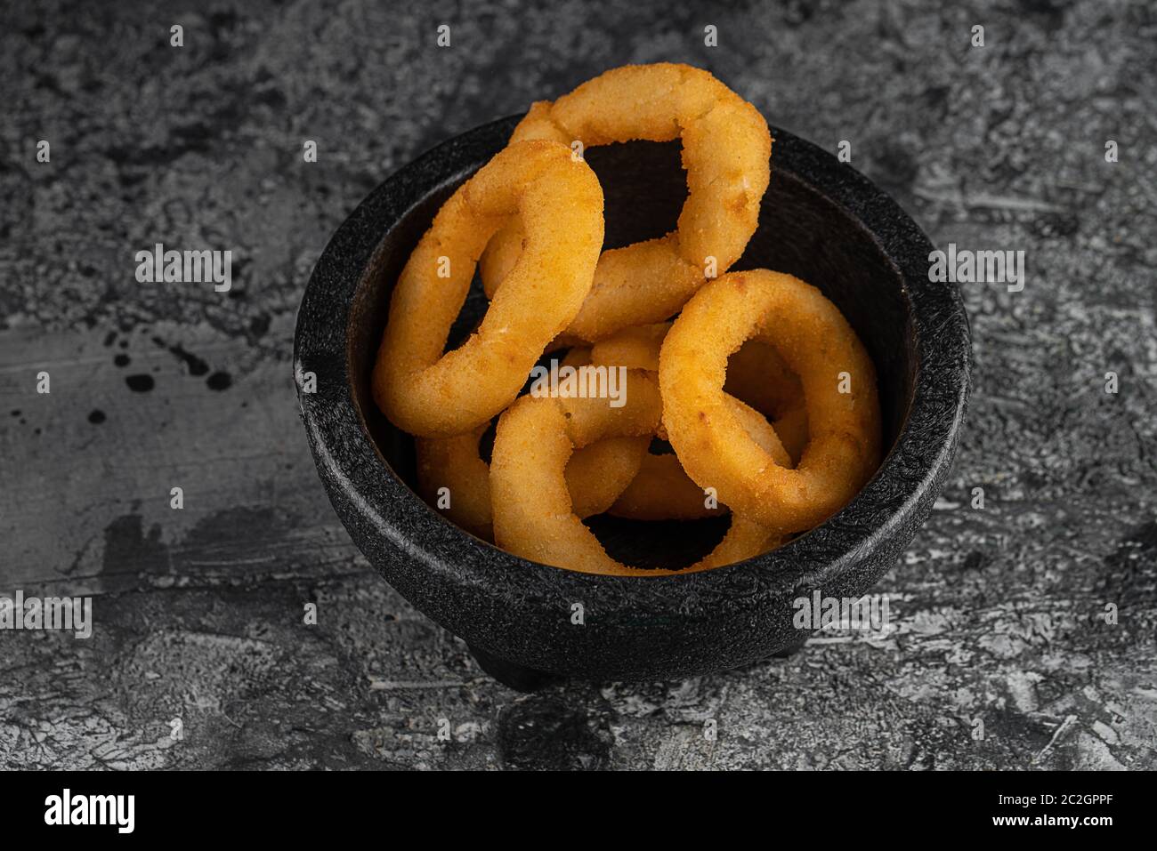 Tasty bacon wrapped onion rings on black plate over blue stone background with free space. Top view, flat lay Stock Photo