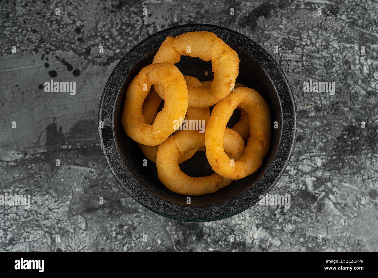 Tasty bacon wrapped onion rings on black plate over blue stone background with free space. Top view, flat lay Stock Photo