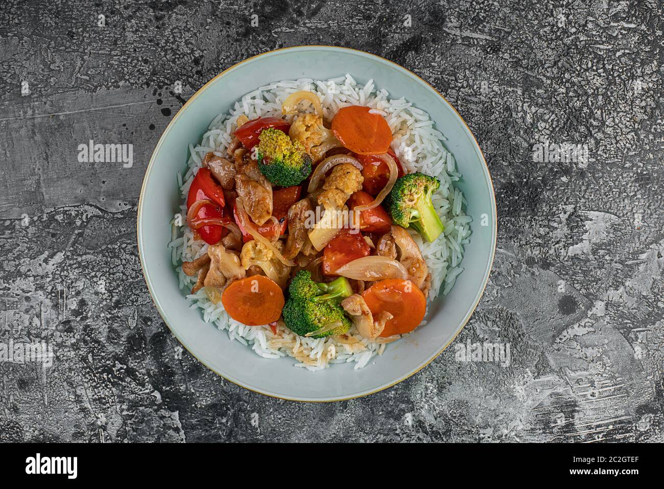 Grilled chicken, rice, spicy chickpeas, avocado, cabbage, pepper buddha bowl on dark background, top view. Delicious balanced food concept Stock Photo