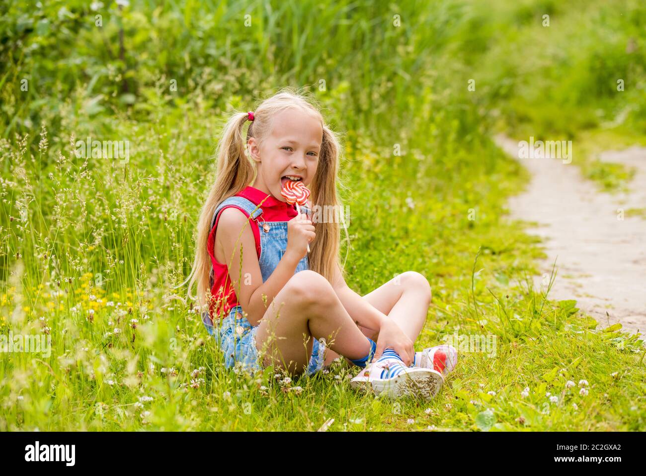 Blonde little girl with long hair and candy on a stick Stock Photo