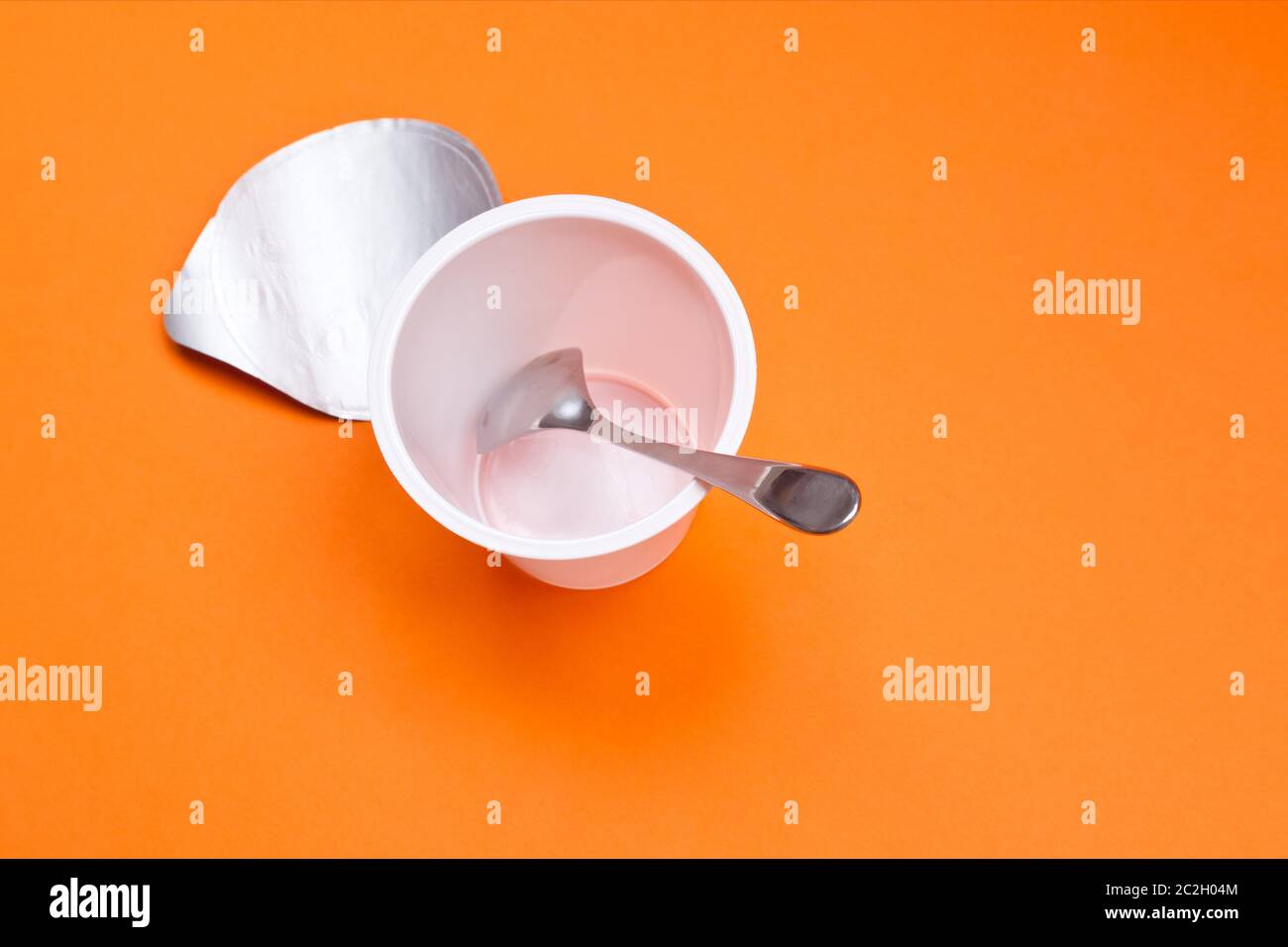 https://c8.alamy.com/comp/2C2H04M/empty-clean-yogurt-cup-with-spoon-on-an-orange-background-2C2H04M.jpg