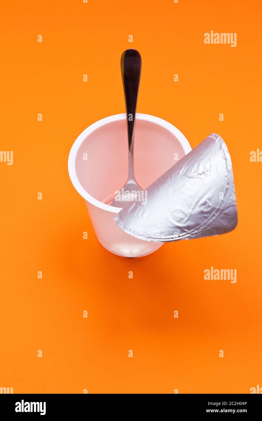 empty clean yogurt cup with spoon on an orange background Stock Photo