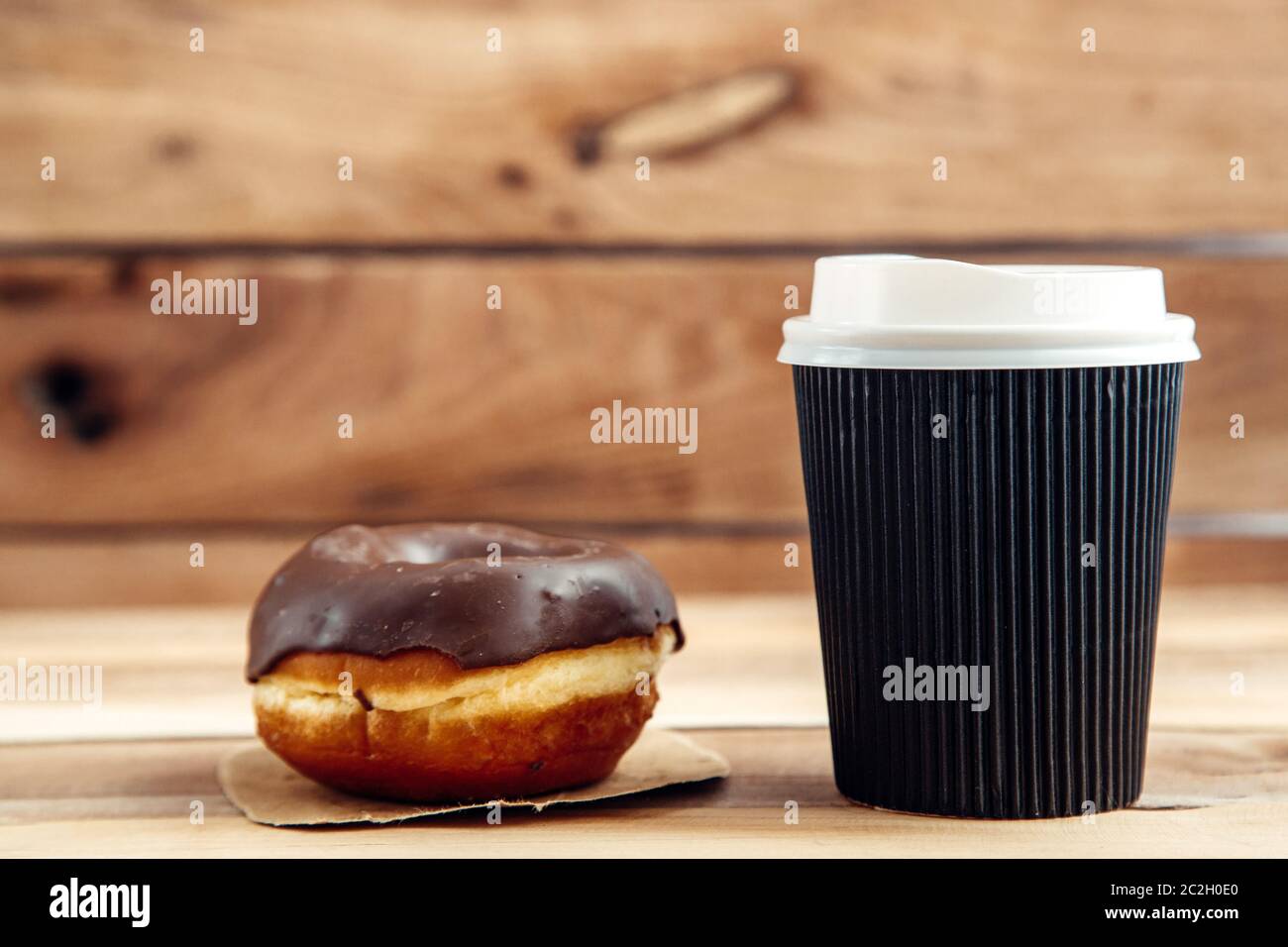 fresh artisan donut and take away coffee, wooden background with copy space Stock Photo