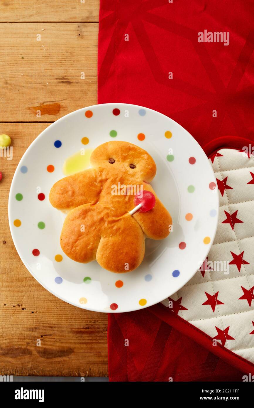 Fresh little Stutenkerl or man made of sweet dough on a polka dot plate on a festive red themed table for traditional Saint Nicholas or St Martins Day Stock Photo