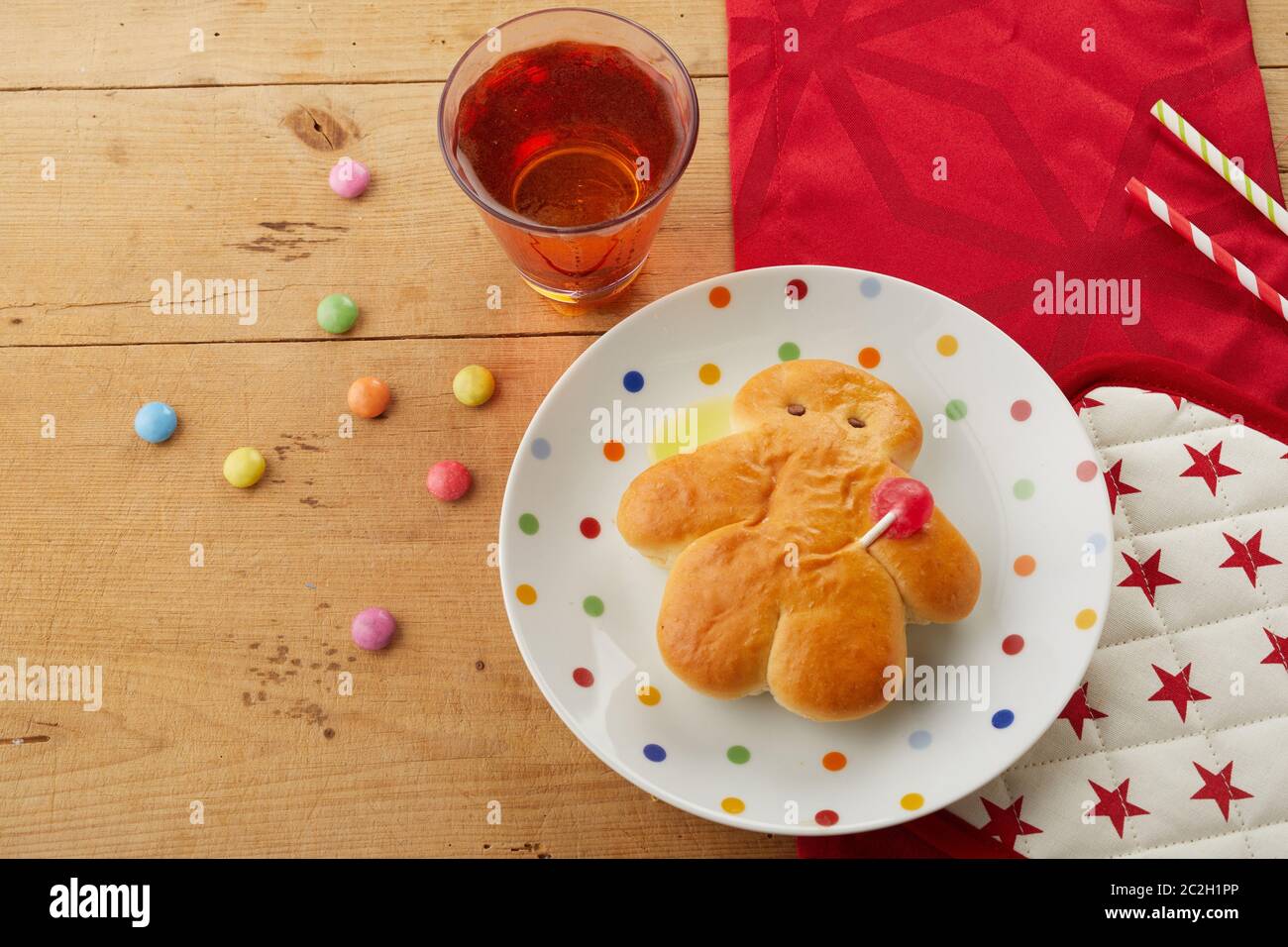 Freshly baked mini Stuten man, a German sweet bread for St Nicholas celebrations, on a red themed festive table with candy and juice Stock Photo