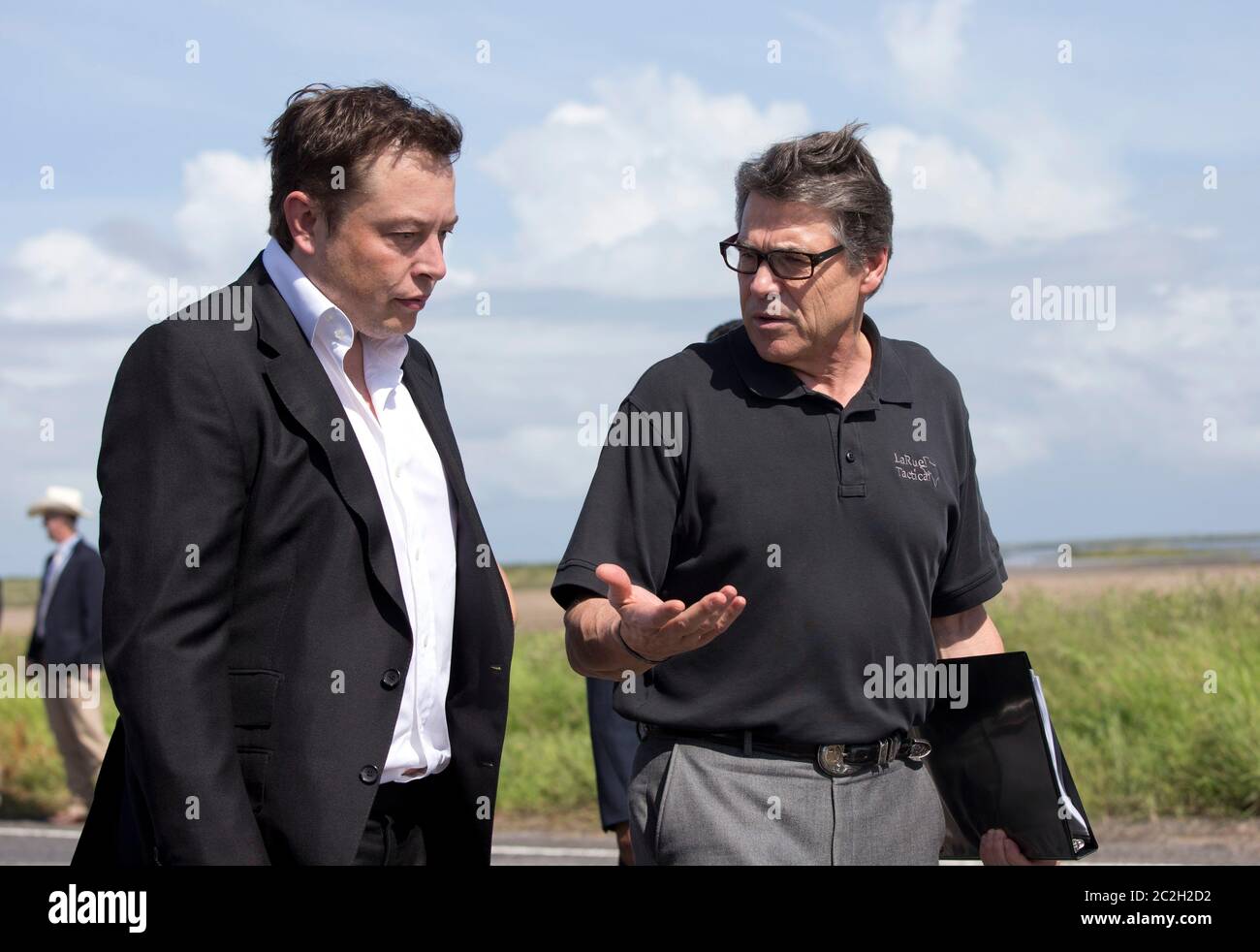 Boca Chica Texas USA, September 23 2014: SpaceX CEO Elon Musk (left) chats with Texas Gov. Rick Perry as they walk to the groundbreaking ceremony on the site of the company's new space port in far south Texas. The remote site east of Brownsville, Texas is two miles from the mouth of the Rio Grande River and Texas' border with Mexico.  ©Bob Daemmrich Stock Photo