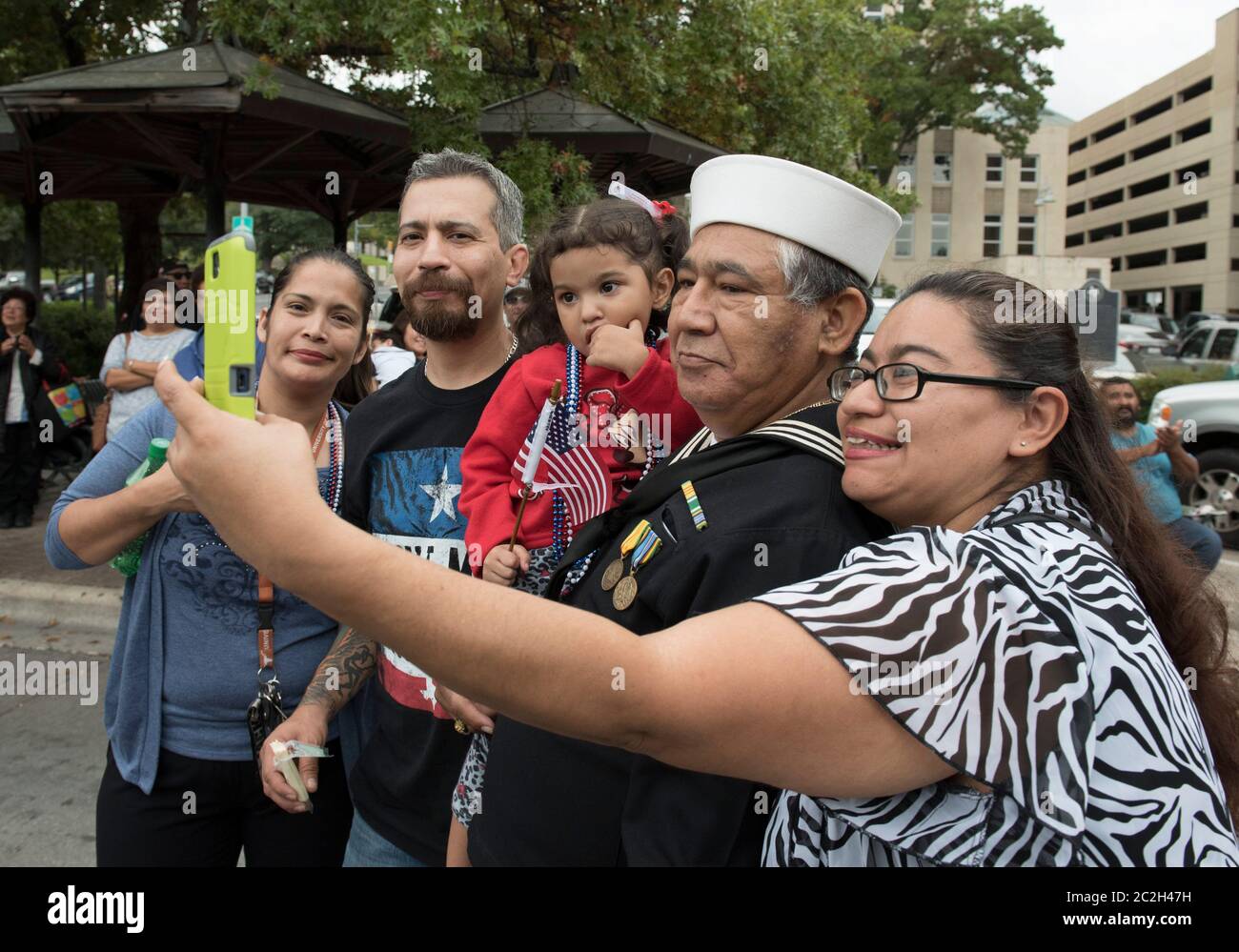 Austin Texas USA, November 11 2015: After losing his home during recent Texas flooding, U.S. Navy veteran Juan DeSantiago (second from right) of Austin gathers his family for a portrait during the Veterans Day parade up Congress Avenue.  ©Bob Daemmrich Stock Photo