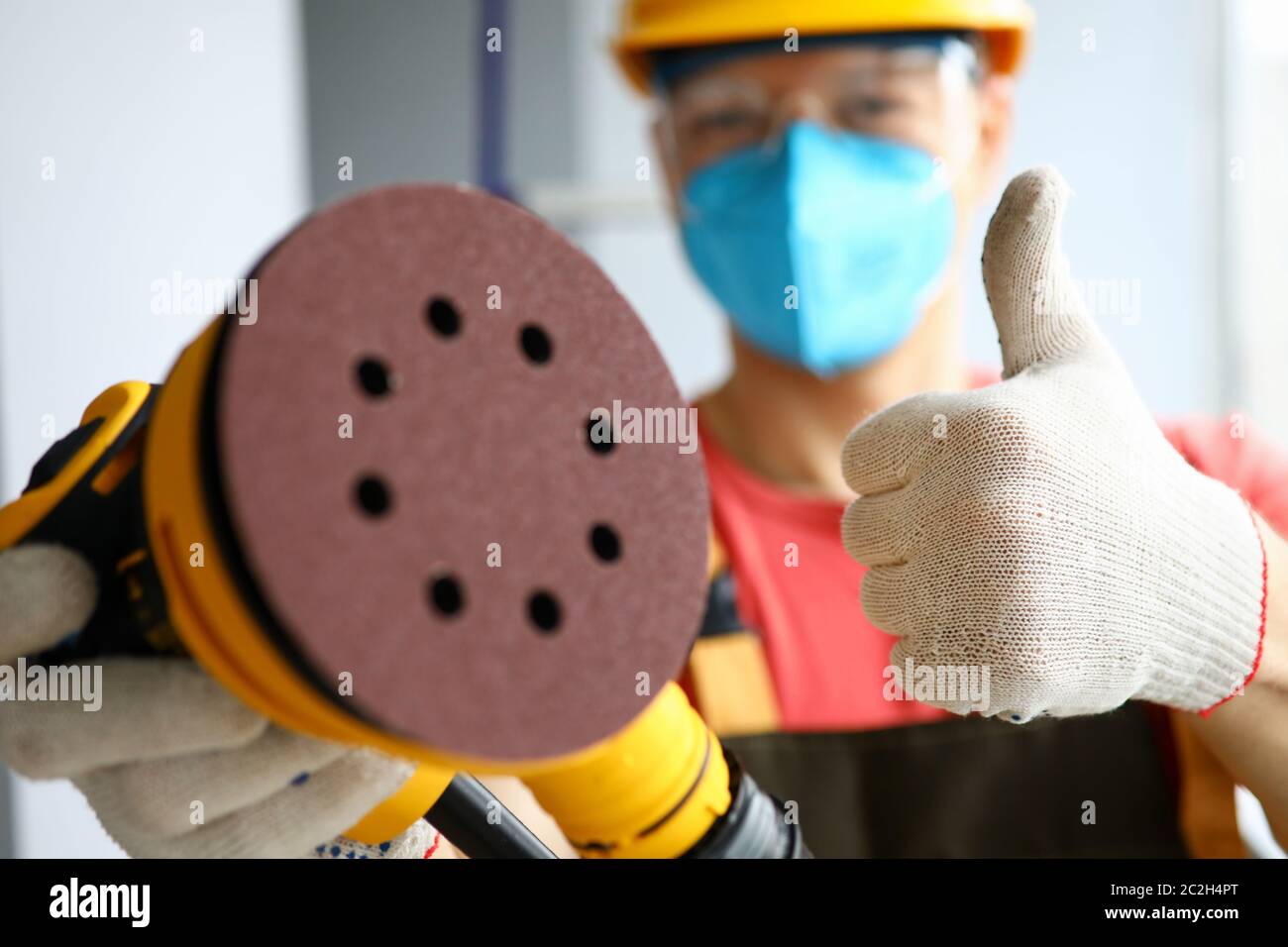 Masked carpenter holds tool and shows gesture ok Stock Photo