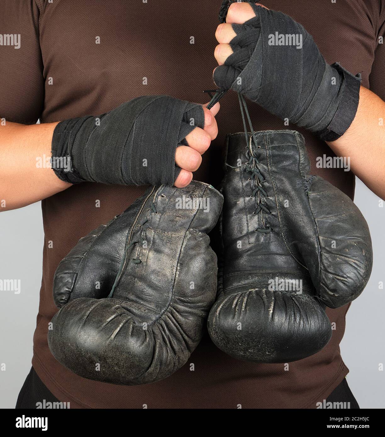 athlete in brown clothes holds very old black vintage leather boxing