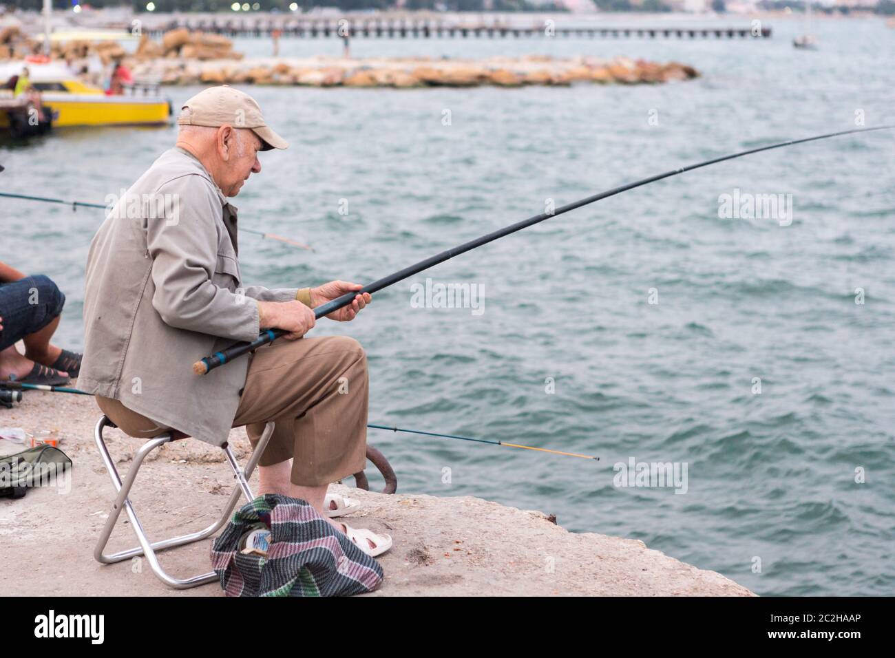 old man fishing on a fishing rod in the sea, in the evening Stock Photo