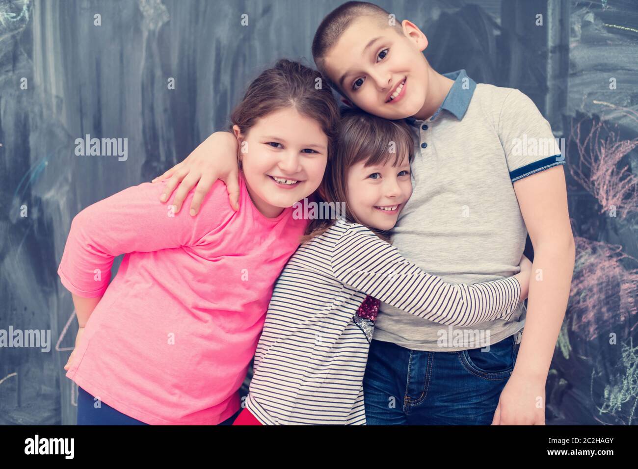 group of kids hugging in front of chalkboard Stock Photo