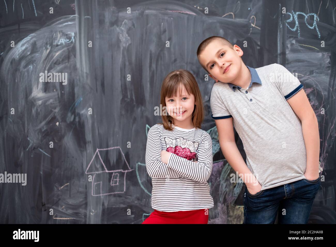 boy and little girl standing in front of chalkboard Stock Photo