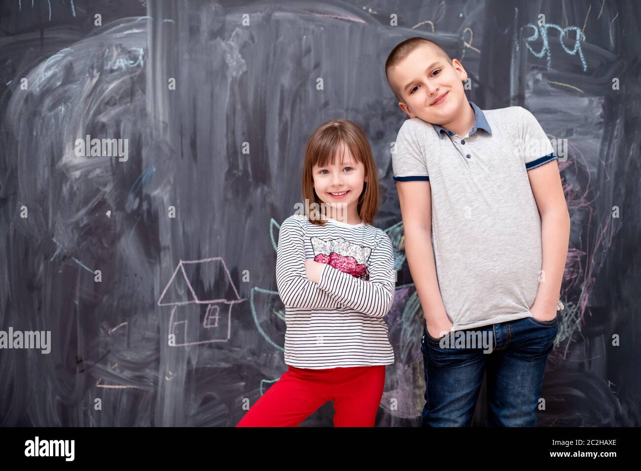 boy and little girl standing in front of chalkboard Stock Photo