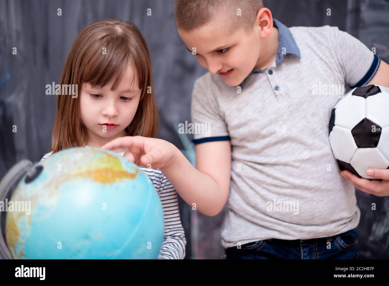 boy and little girl using globe of earth in front of chalkboard Stock Photo