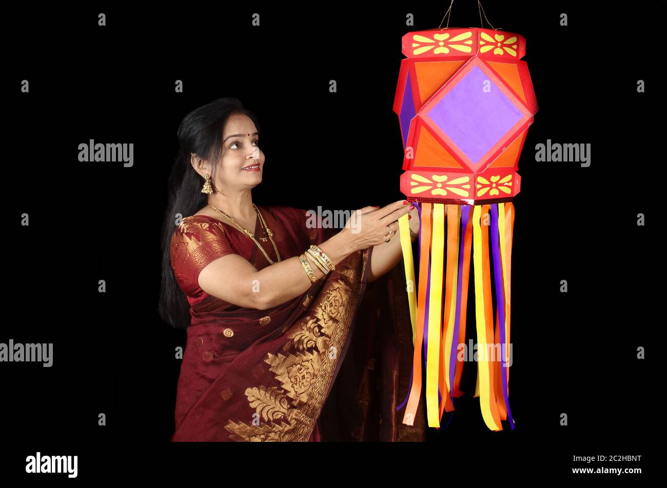 An Indian woman looking at the traditional Diwali lantern during Diwali festival in India, on the backdrop of Diwali fireworks. Stock Photo