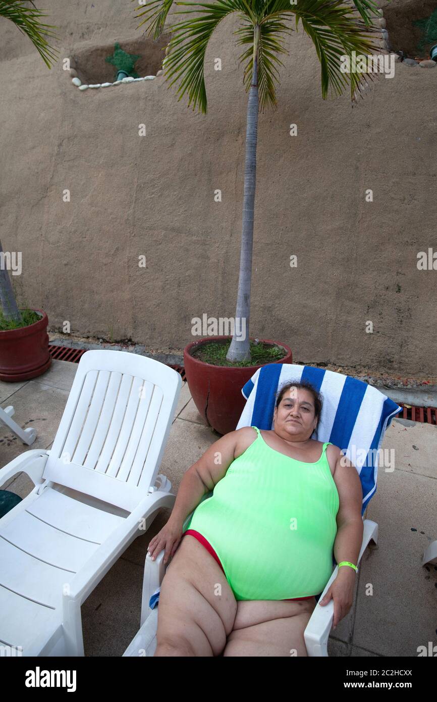Marbella sits in a white plastic sunbed on the side of the hotel's swimming pool in Acapulco, Mexico on September 8, 2013. Marbella Aguilar Sosa is a Stock Photo