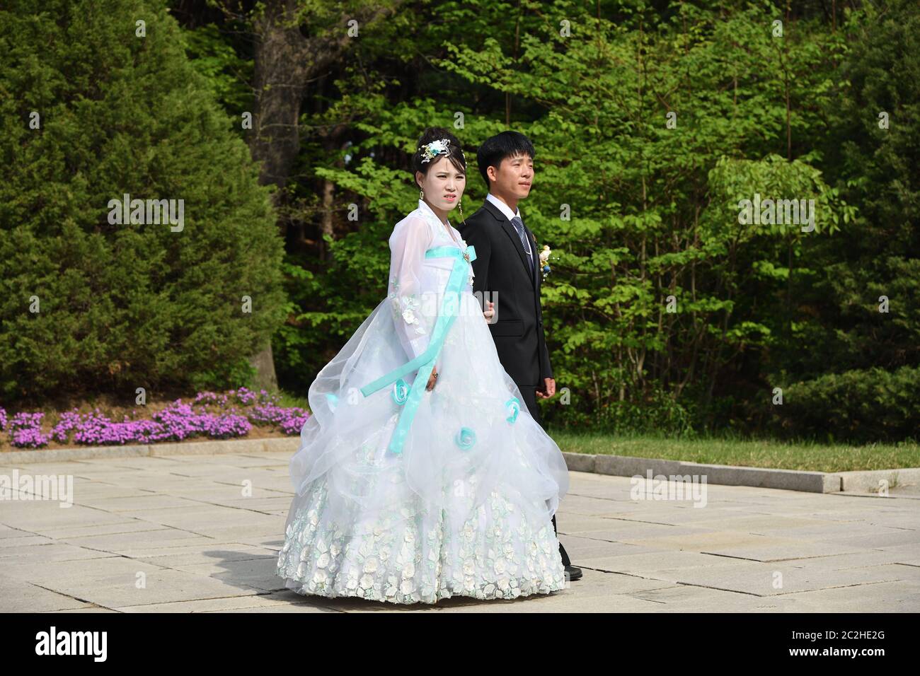 Kaesong, North Korea - May 5, 2019: Young Korean couple in historical place - Tomb of King Wanggon. Newlyweds are photographed against the park backgr Stock Photo