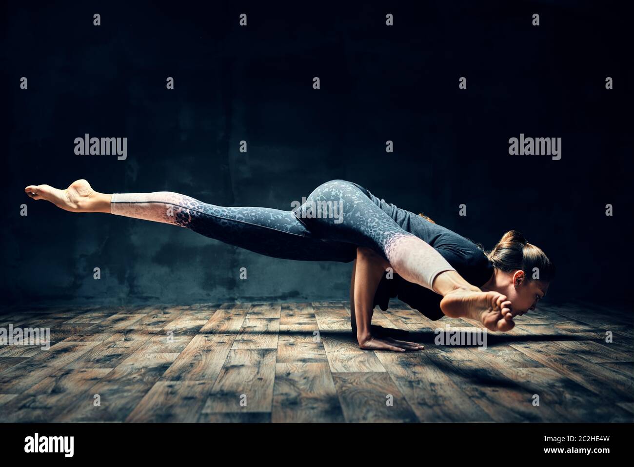 Young woman practicing yoga doing hurdler pose in dark room Stock Photo -  Alamy