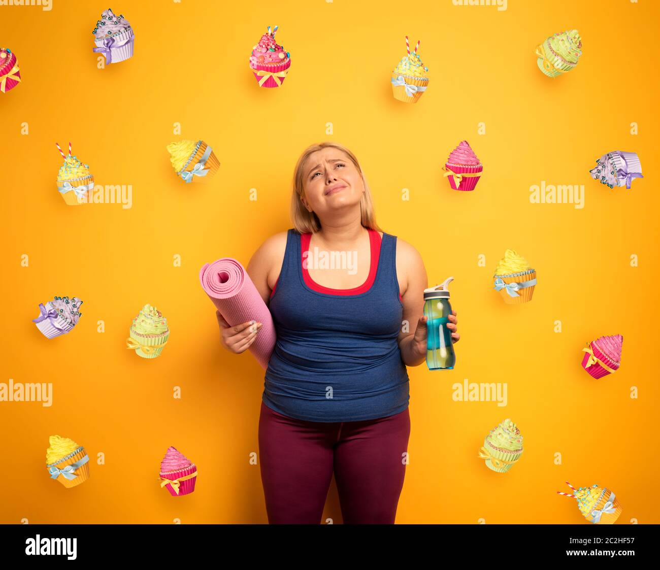 Fat girl thinks to eat sweets instead of do gym. yellow background Stock Photo