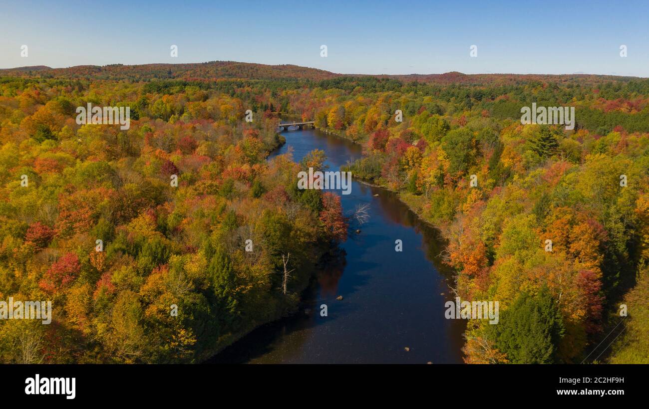 Fall color is more saturated at sunset over the Oswegatche River Adirondack Park Mountains New York Stock Photo