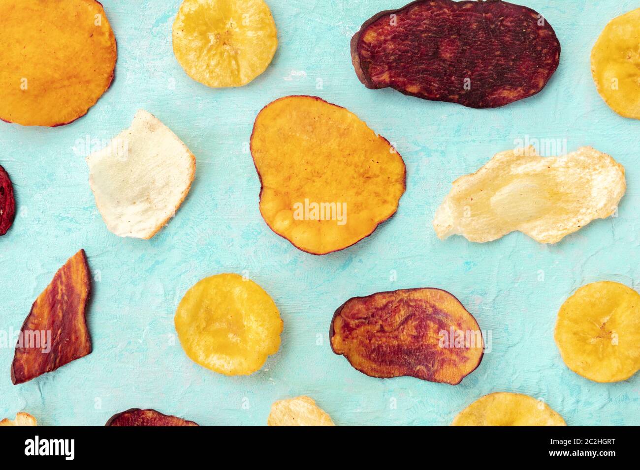 Dry fruit and vegetable chips, top shot. Healthy vegan snack, an organic food flat lay pattern on a teal blue background Stock Photo