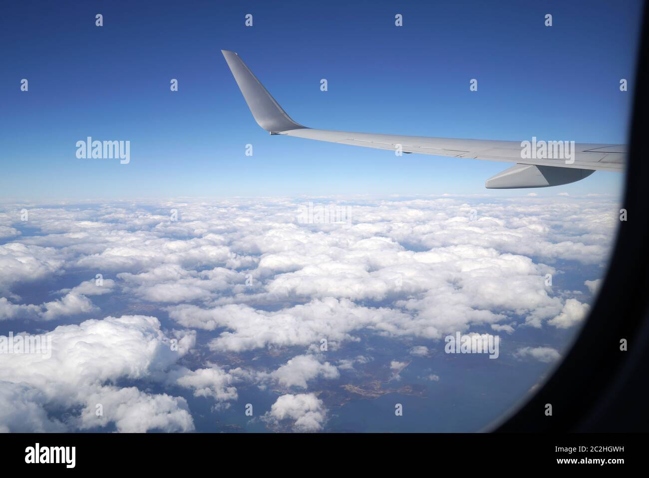 Wing of an airplane flying above the clouds, from the window of the