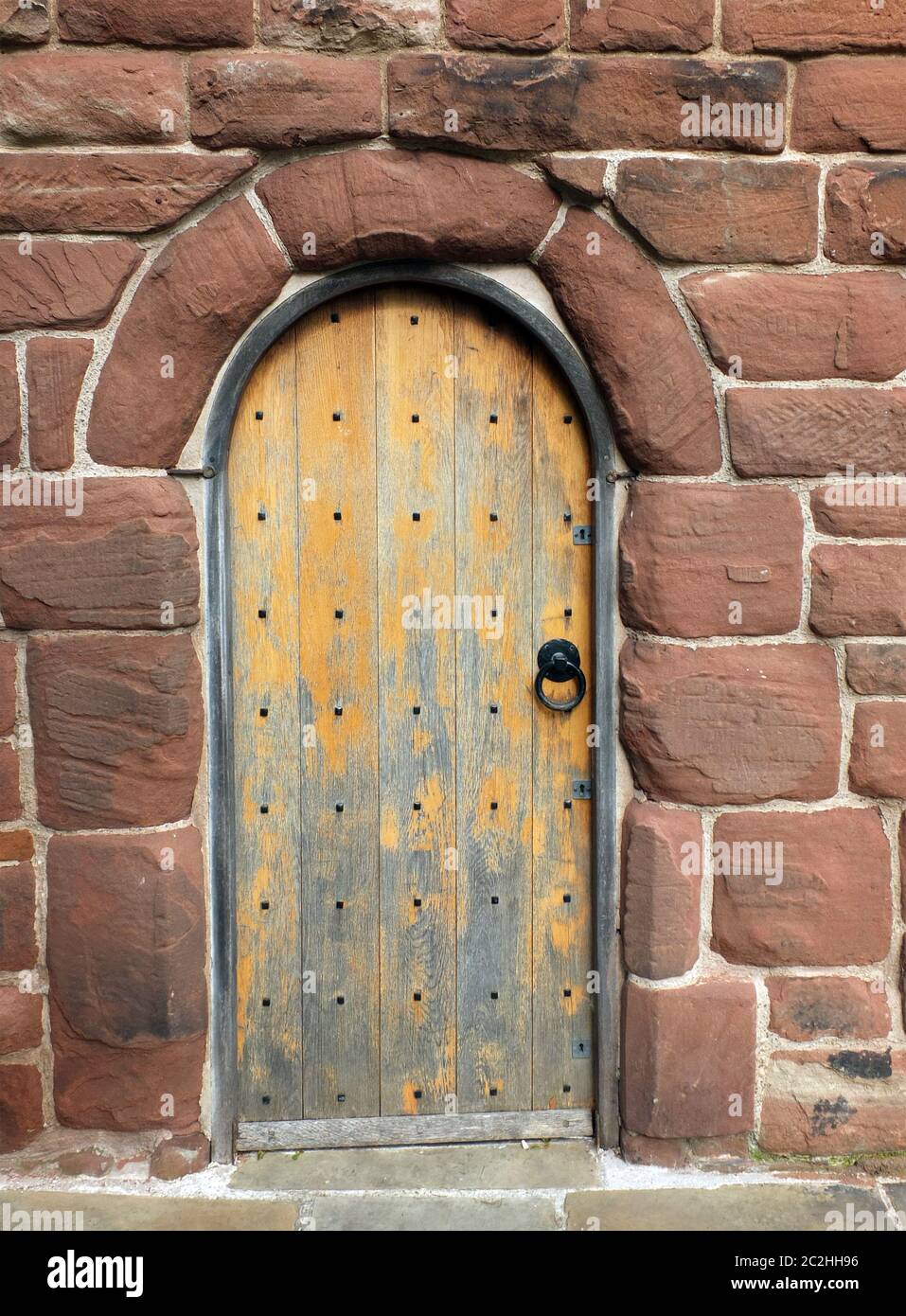 an ancient brown wooden door in a red sandstone medieval wall Stock ...