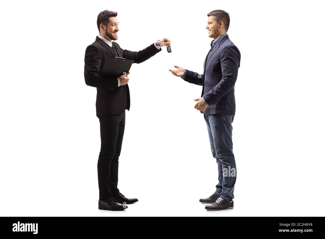Full length profile shot of a car salesman giving car keys to a man isolated on white background Stock Photo
