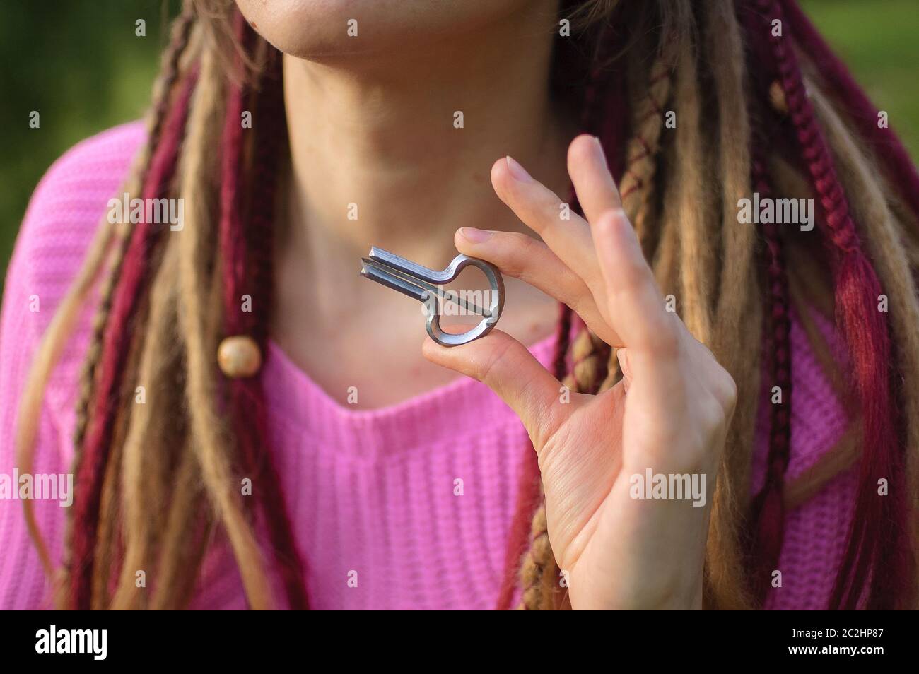 Portrait of young woman with long dreadlocks holding traditional hutsul drymba or jew's-harp, the oldest musician instrument in the world, near her Stock Photo