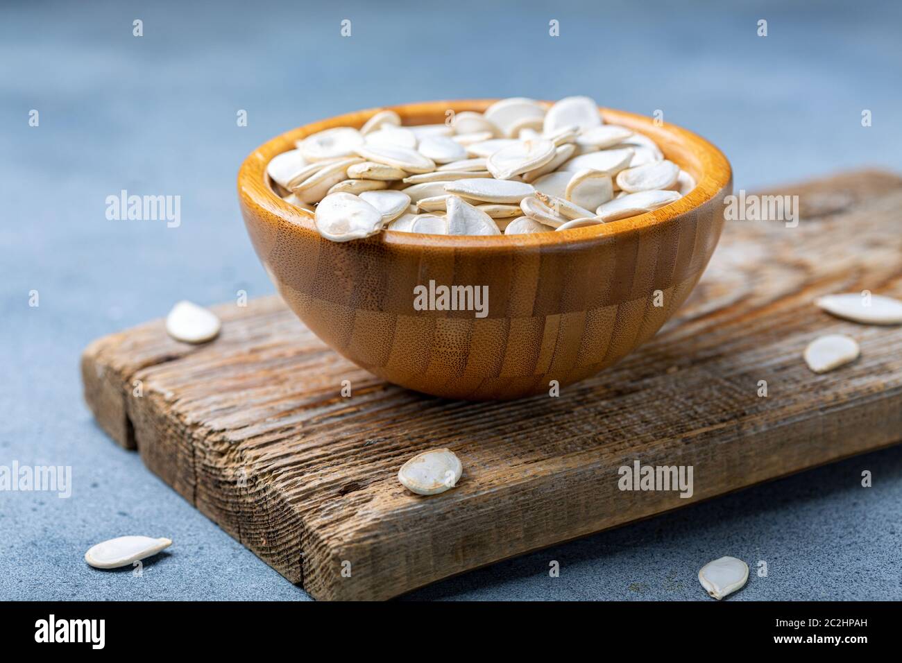 Unpeeled pumpkin seeds in a wooden bowl. Stock Photo