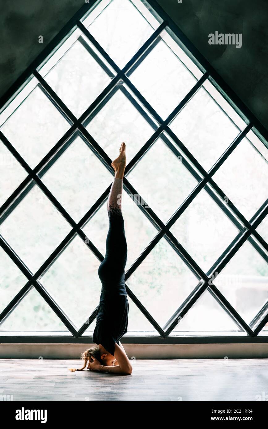 Young attractive yogi woman practicing yoga standing in supported headstand pose Stock Photo