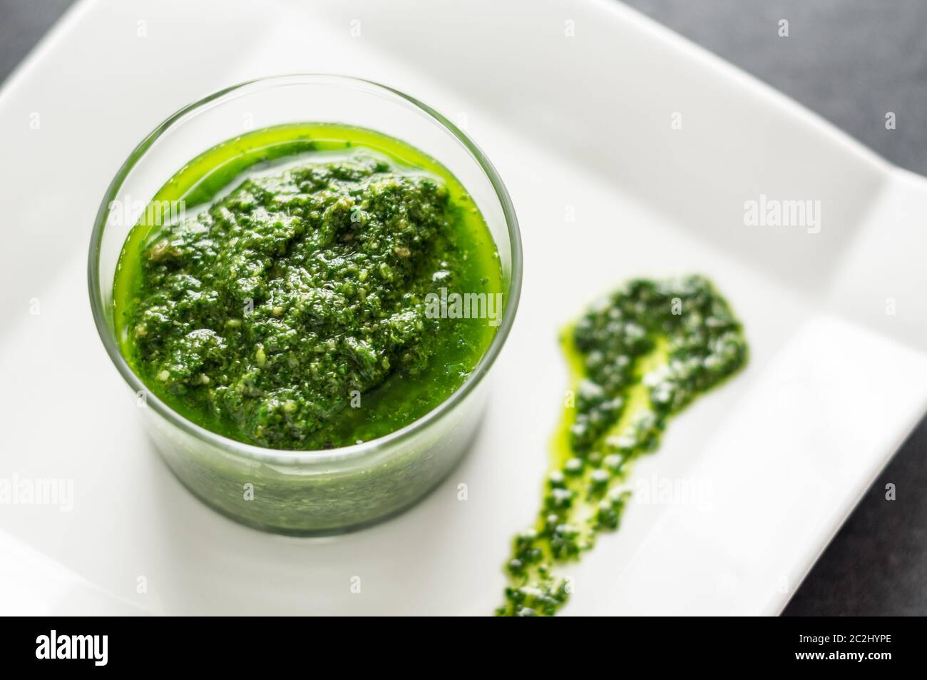 Fresh homemade basil pesto sauce in a glass jar. Originally from italy, pesto is commonly made with basil and used as a sauce for pasta. Stock Photo