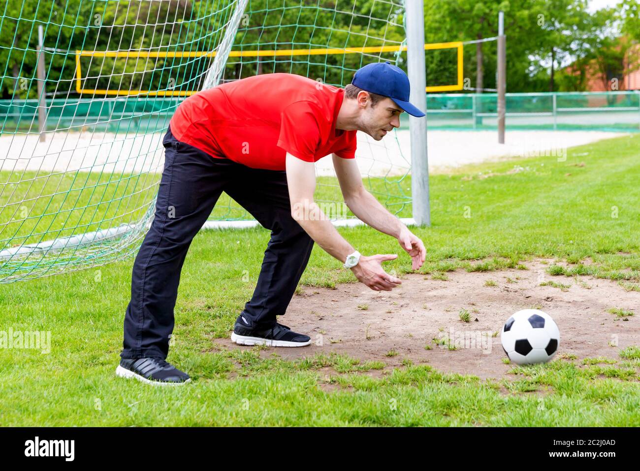Goalkeeper with cap and soccer ball on a soccer field Stock Photo Alamy