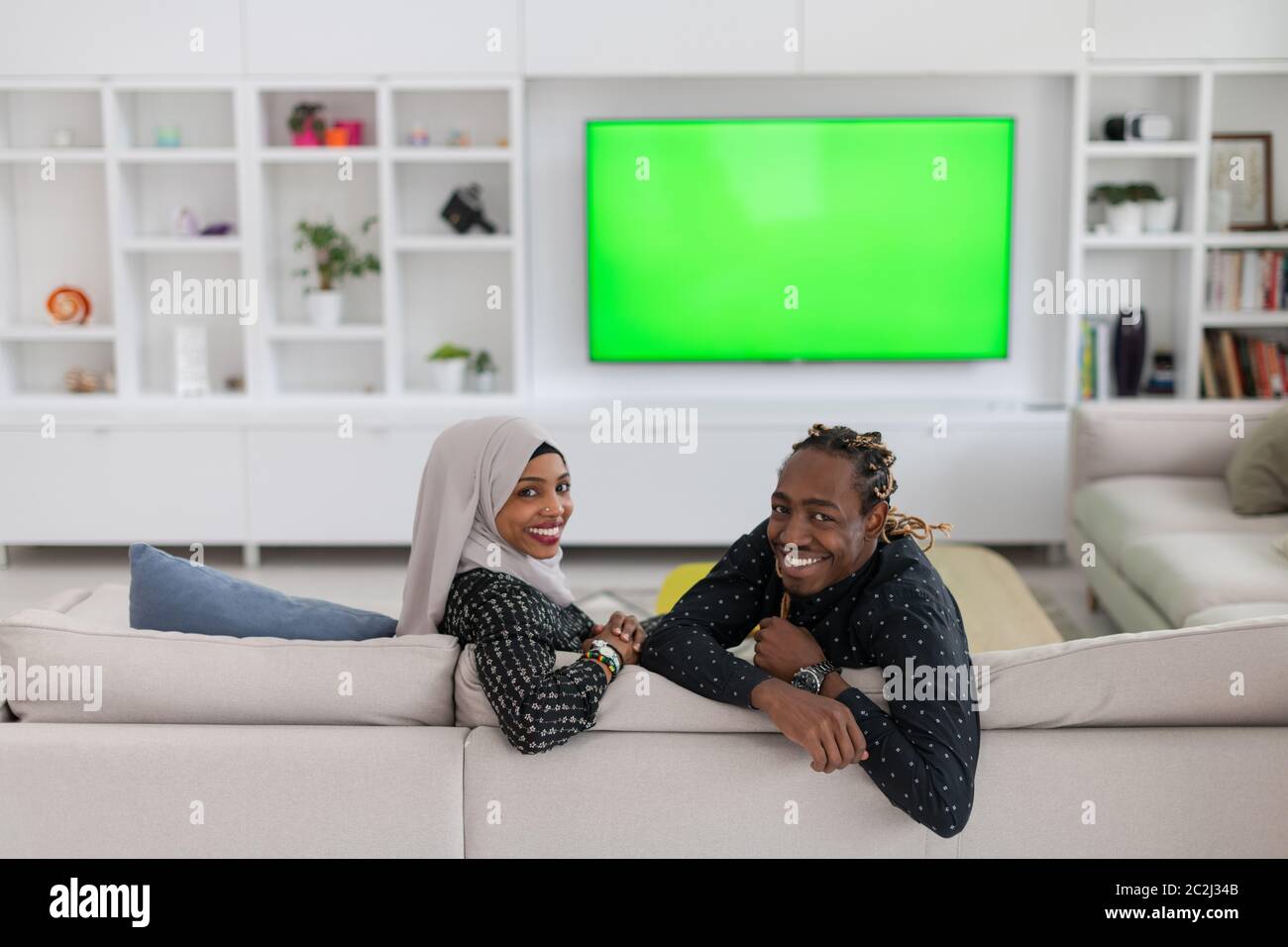 African Couple Sitting On Sofa Watching TV Together Stock Photo - Alamy