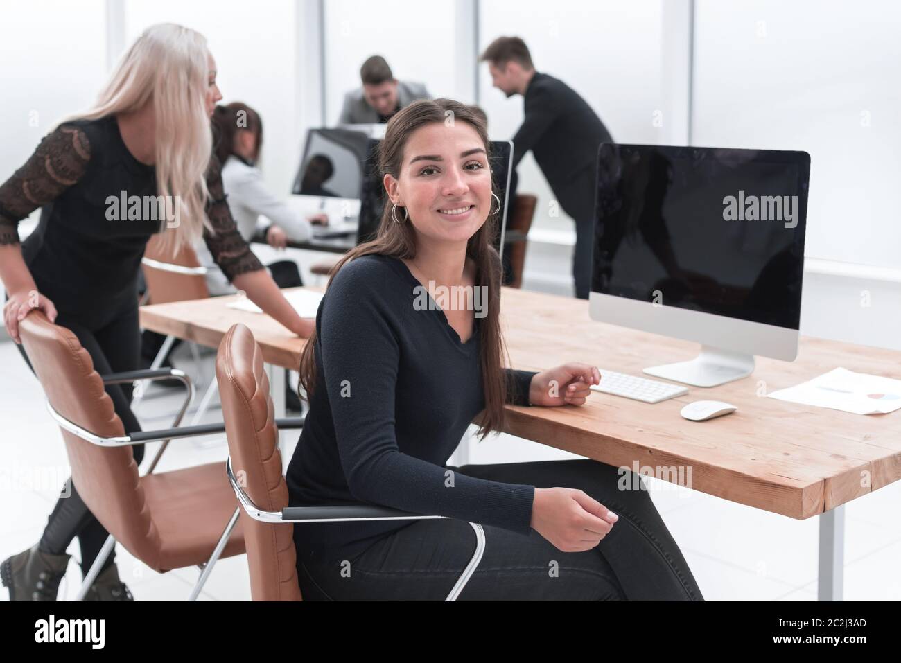 smiling young business woman sitting at an office Desk Stock Photo - Alamy