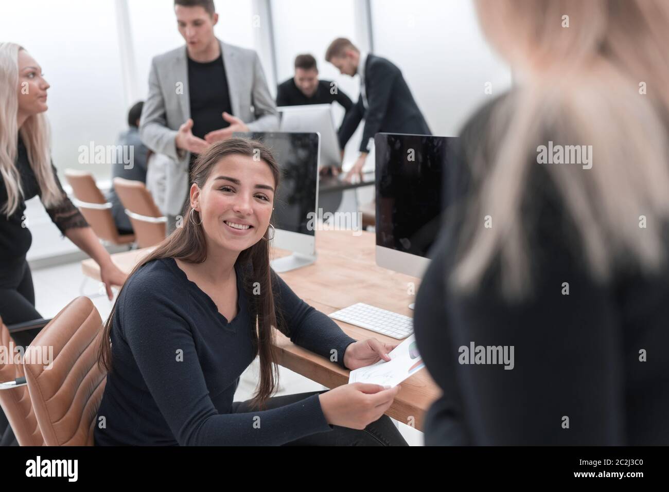 smiling young business woman sitting at an office Desk Stock Photo - Alamy