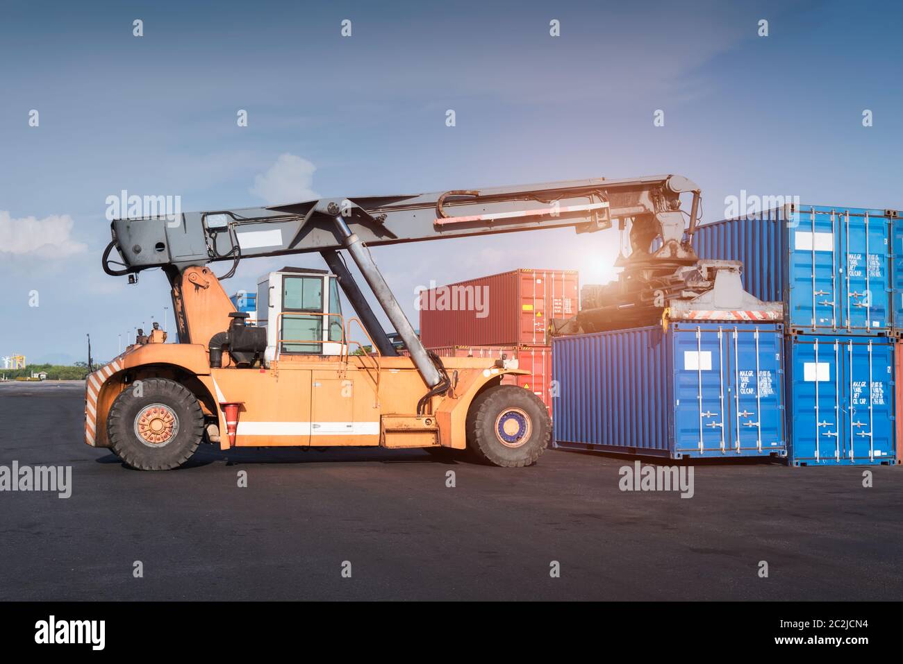Forklift truck lifting Cargo containers in shipping dock yard for