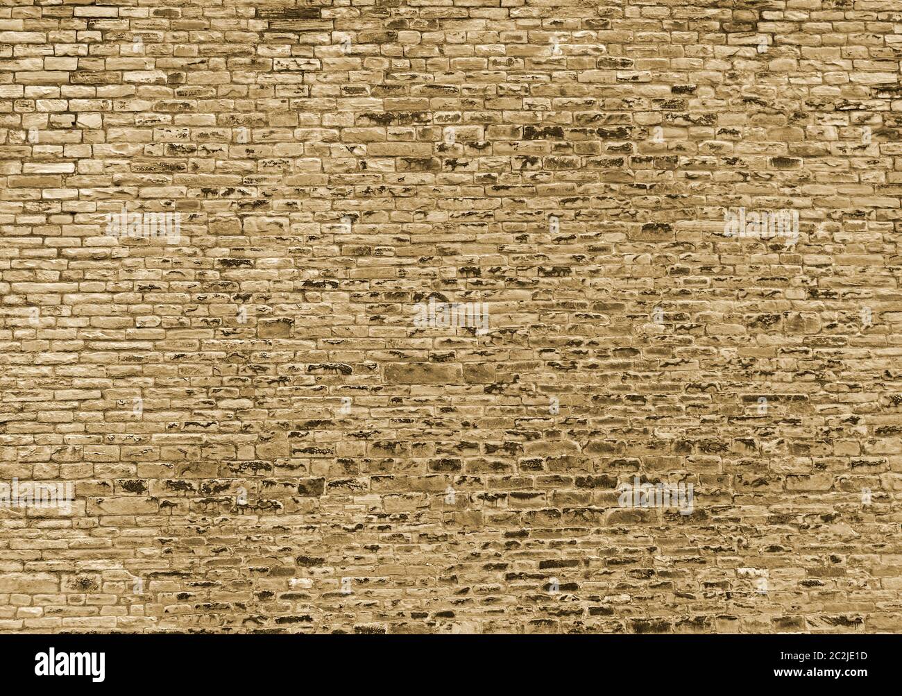 a sepia toned large rough textured brown wall made of old sandstone bricks Stock Photo