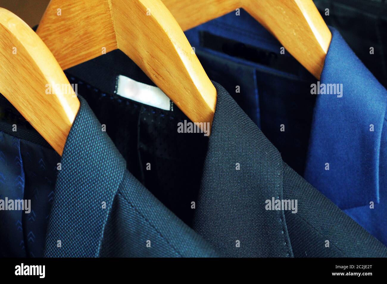 Row of men's suits hanging in closet. Stock Photo
