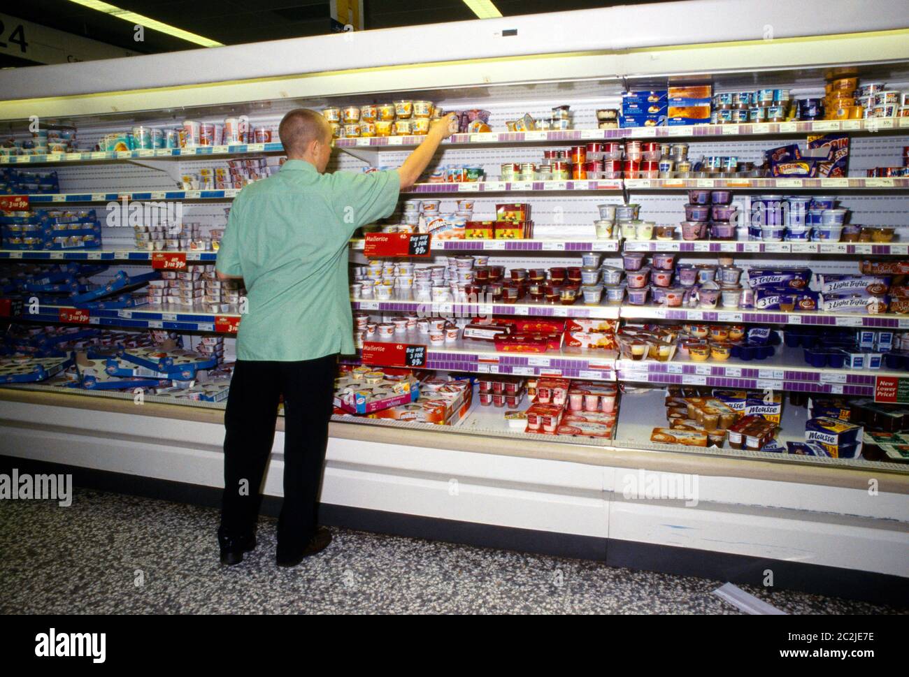 Employee Stacking Shelves in Safeways Supermarket Surrey England Stock