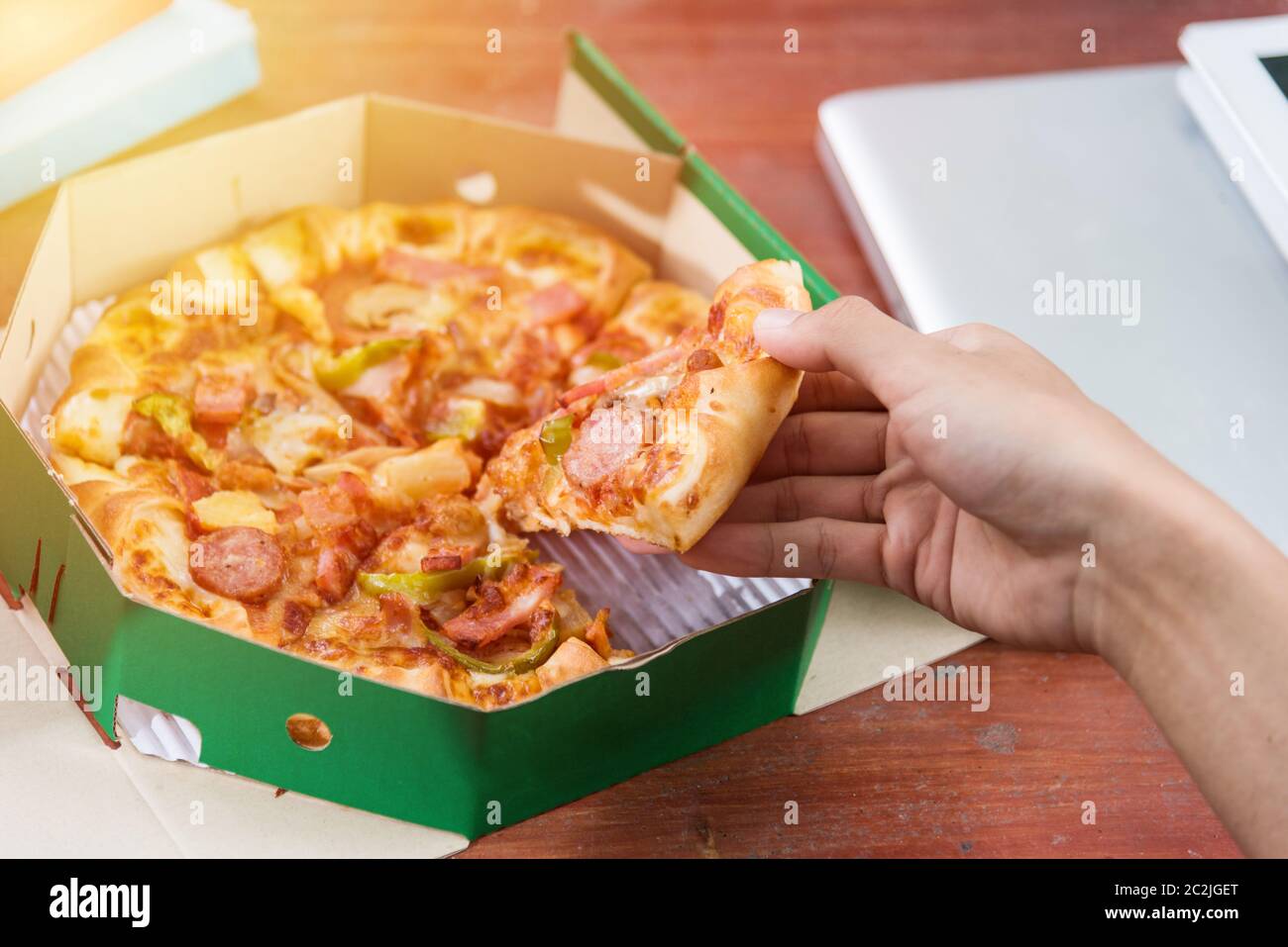 Hands taking pizza slices from green box Stock Photo