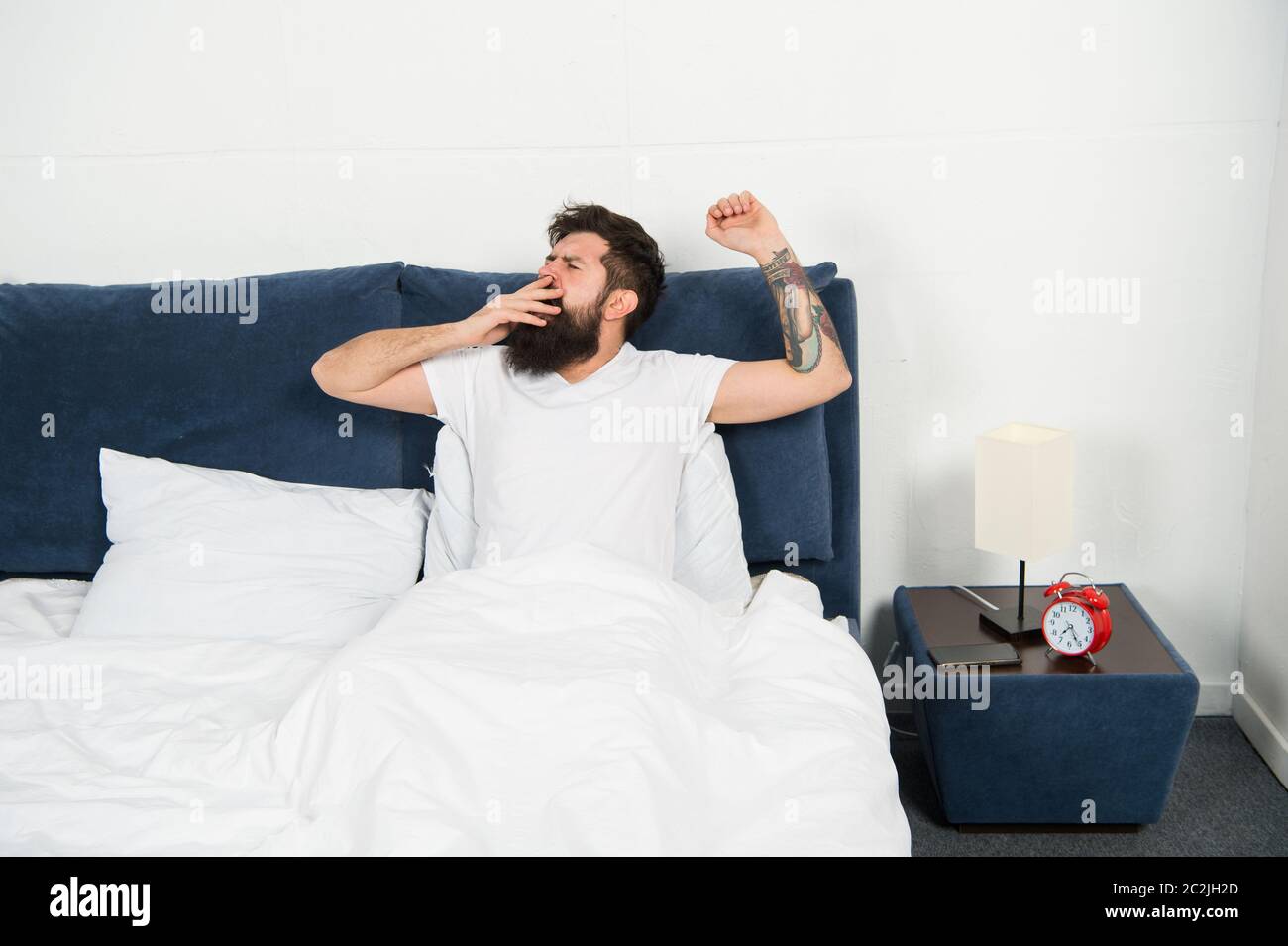 Bed is so comfortable in morning. Hipster give long yawns in bed. Bearded man stay in bed after wakeup. Bed time routine. Bedroom. Getting the rest your body needs. Stock Photo