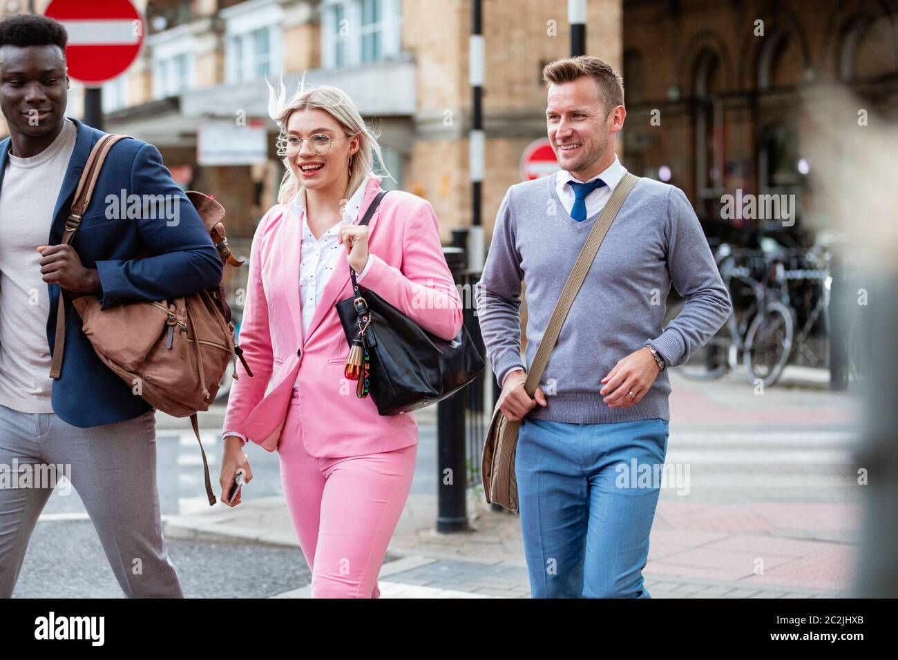 A businesswoman walking with two businessmen home from work through the city. Stock Photo