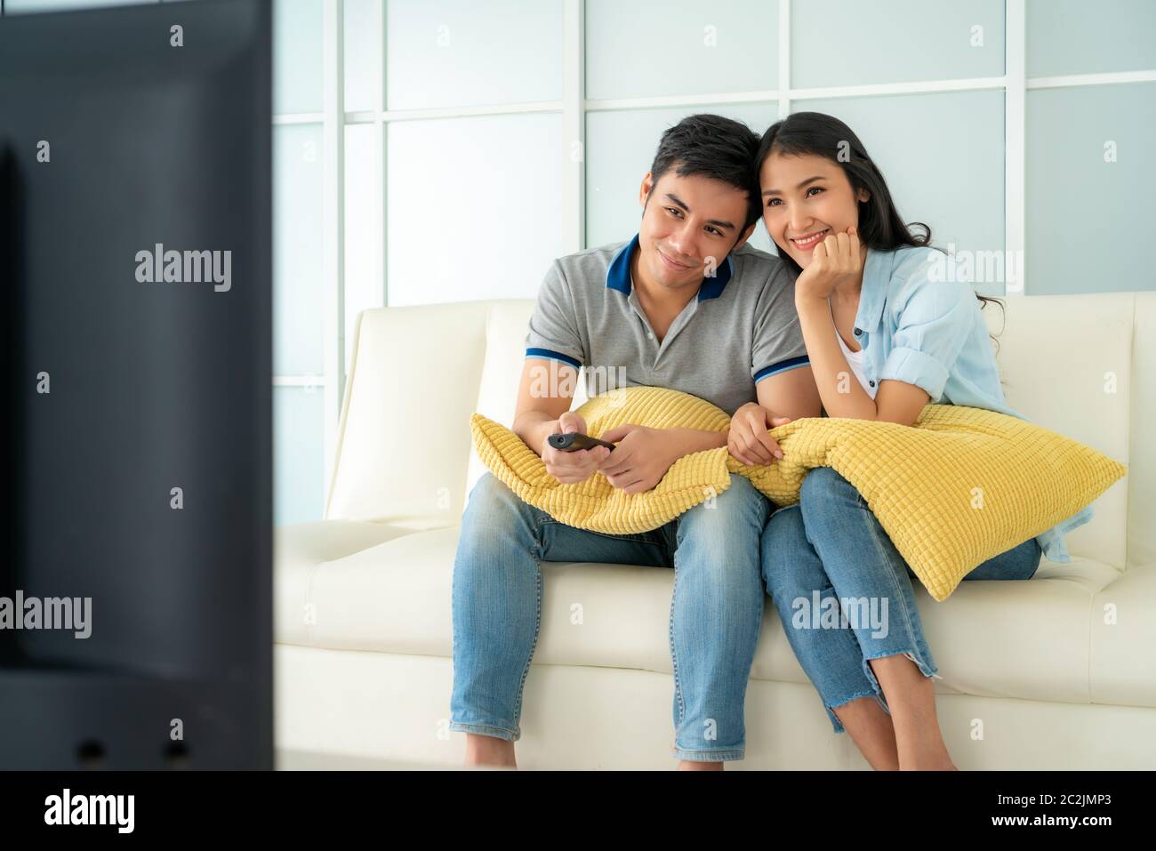 Asian happy fcouple sitting in sofa and watching television at home concept of family values, vacation day, holiday, happiness or lifestyle. Stock Photo